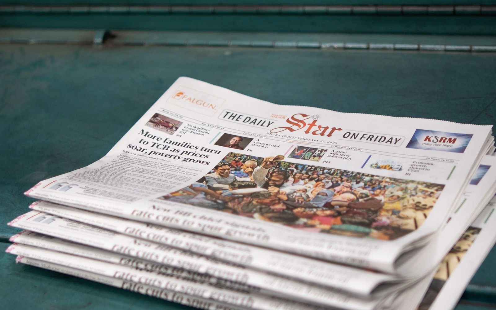 A stack of folded Daily Star newspapers on a teal-painted surface