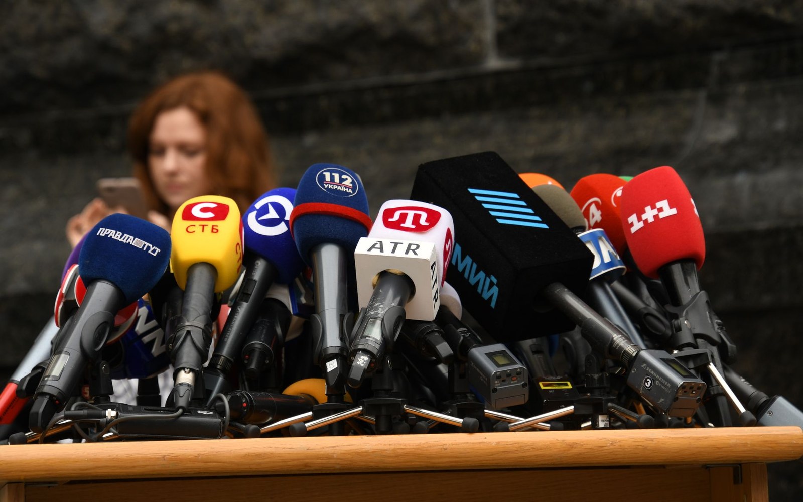Rows of branded microphones from Ukrainian broadcasters crowd a podium at a press conference