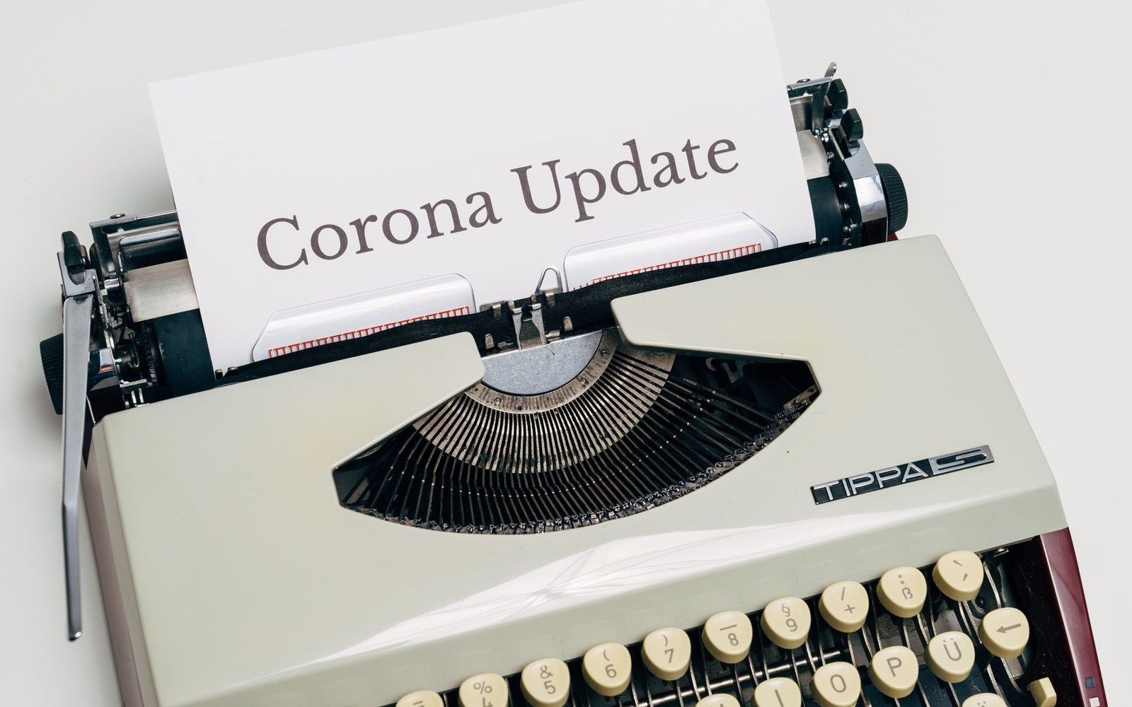 A vintage typewriter with paper reading "Corona Update" rolled into the carriage
