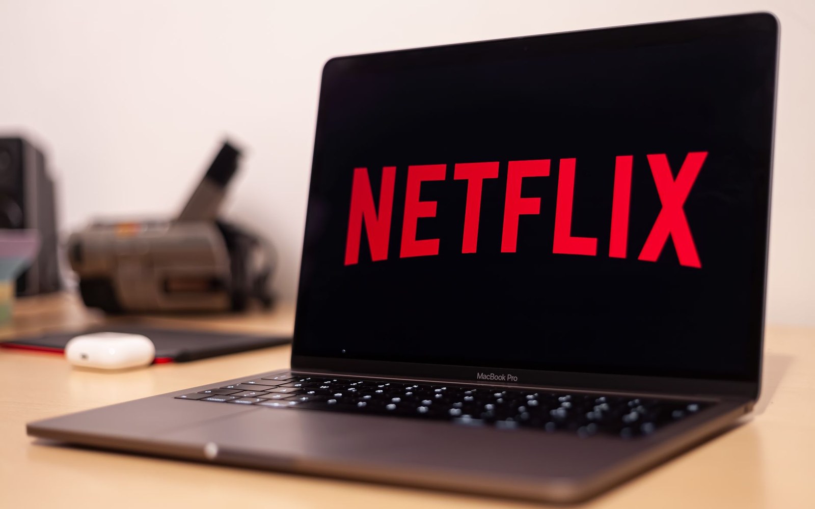 The Netflix logo displayed on a MacBook Pro screen on a wooden desk