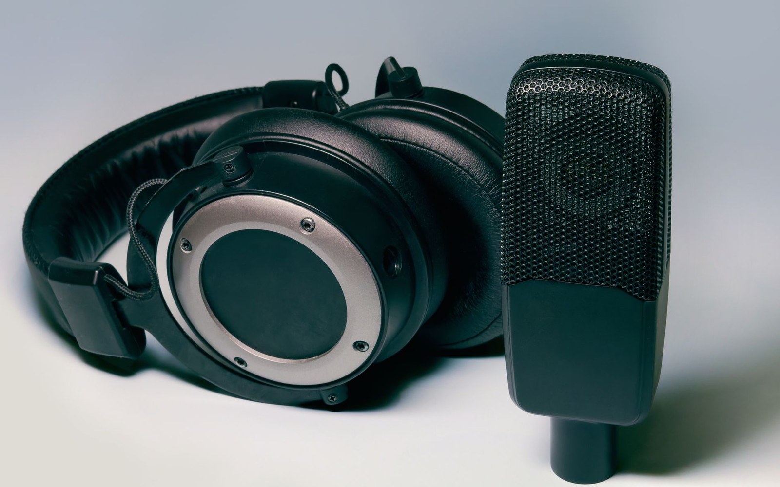 Studio headphones and a condenser microphone on a plain background