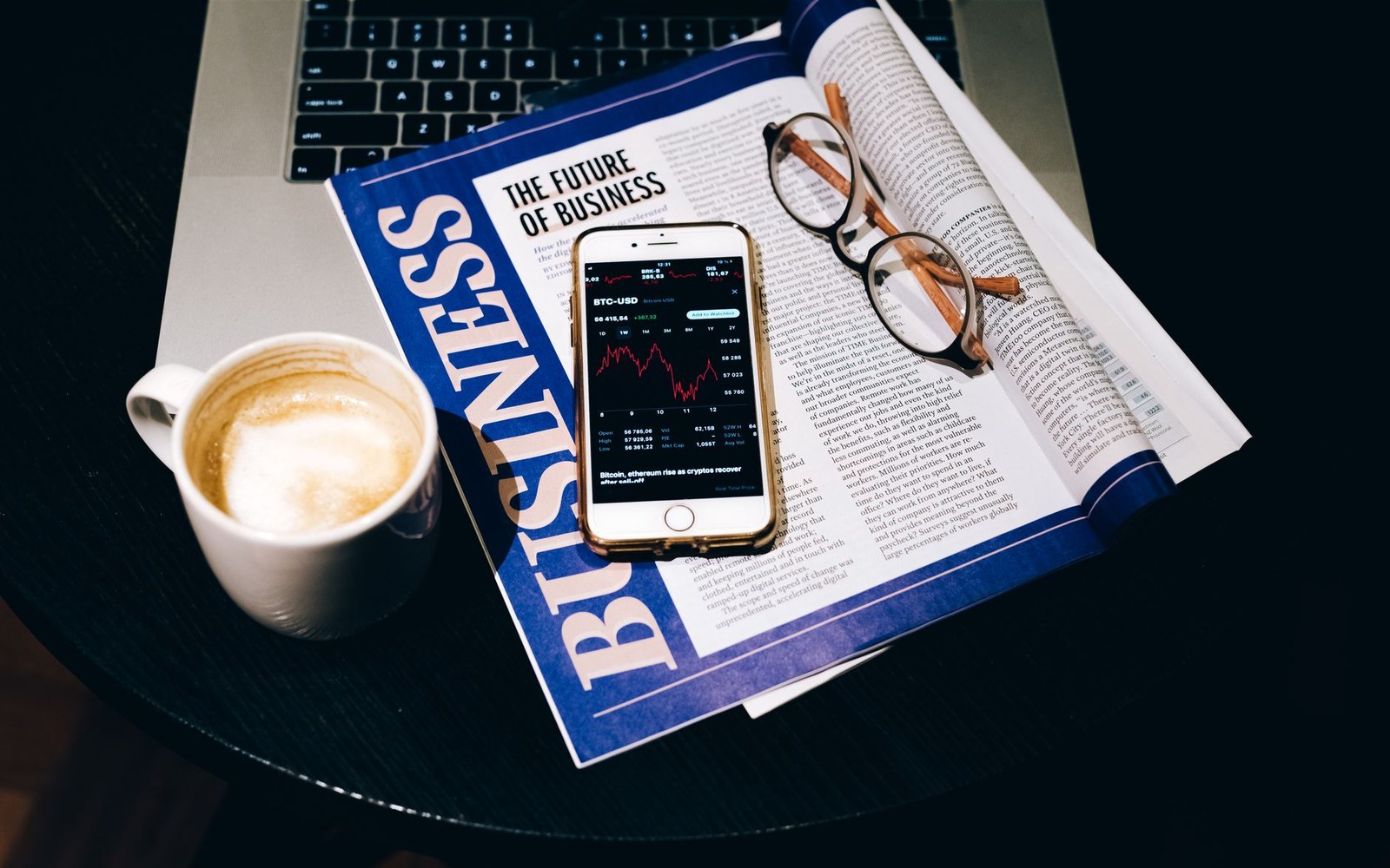 A laptop screen showing a Substack newsletter page beside a folded broadsheet newspaper on a desk